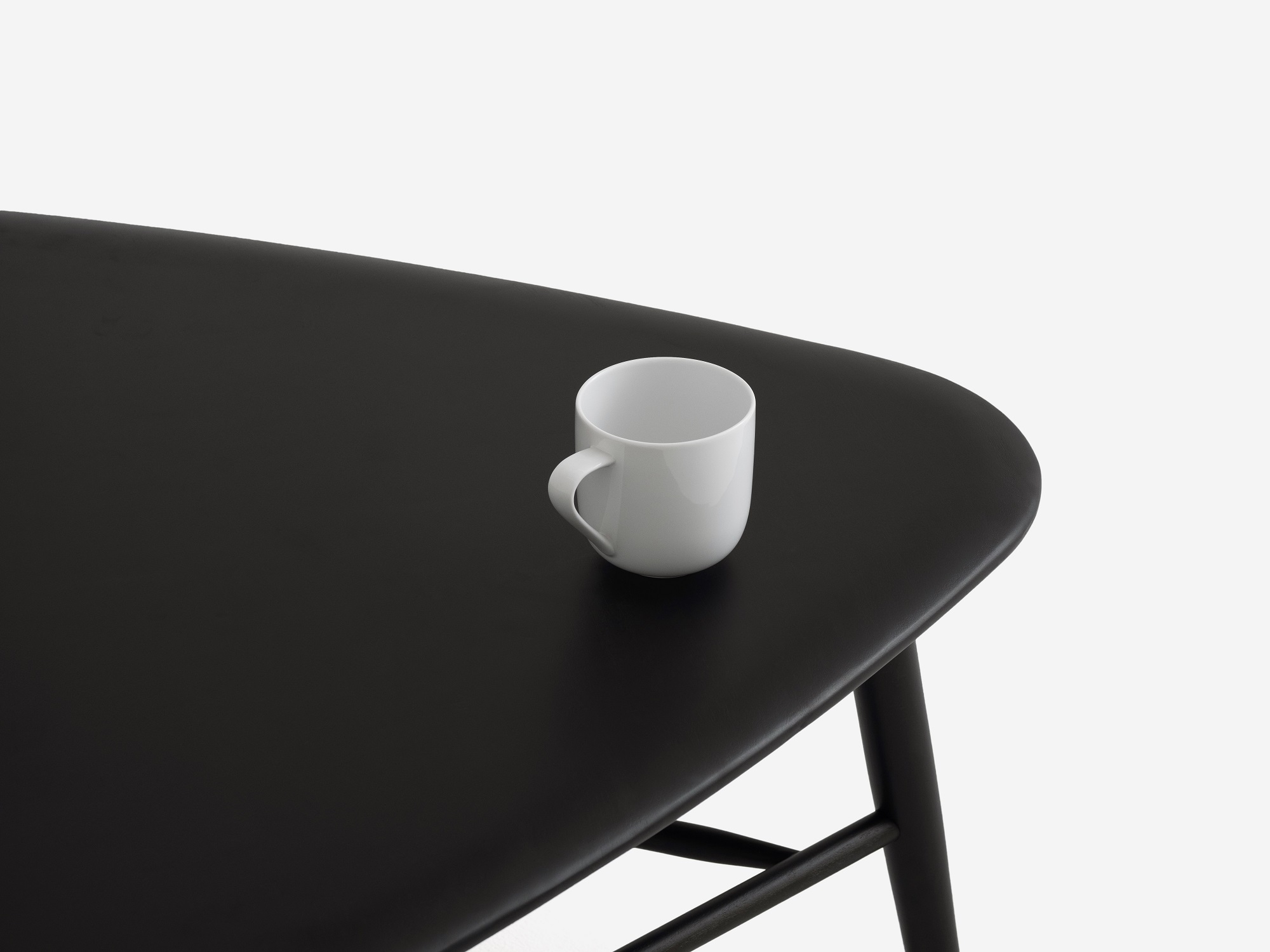 Black tri coffee table with white mug on it detail view